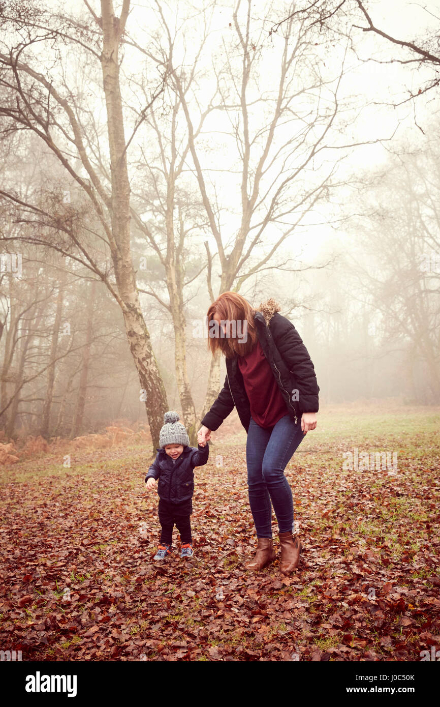 Männliche Kleinkind an Mutters Hand im Wald Stockfoto