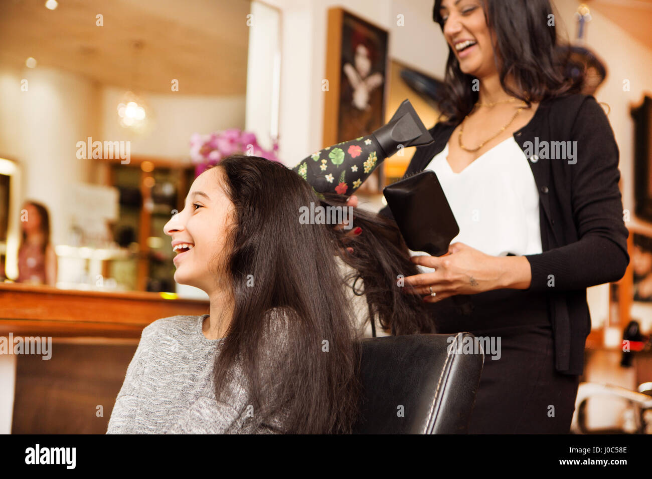 Friseur und Mädchen Lachen ohne Schlag trocken im Friseursalon Stockfoto