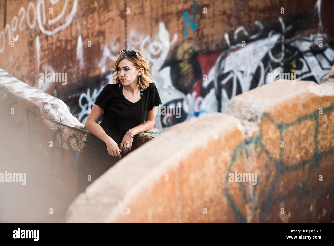 Junge Frau lehnte sich gegen Graffiti-Wand-Mine-Ruinen Stockfoto
