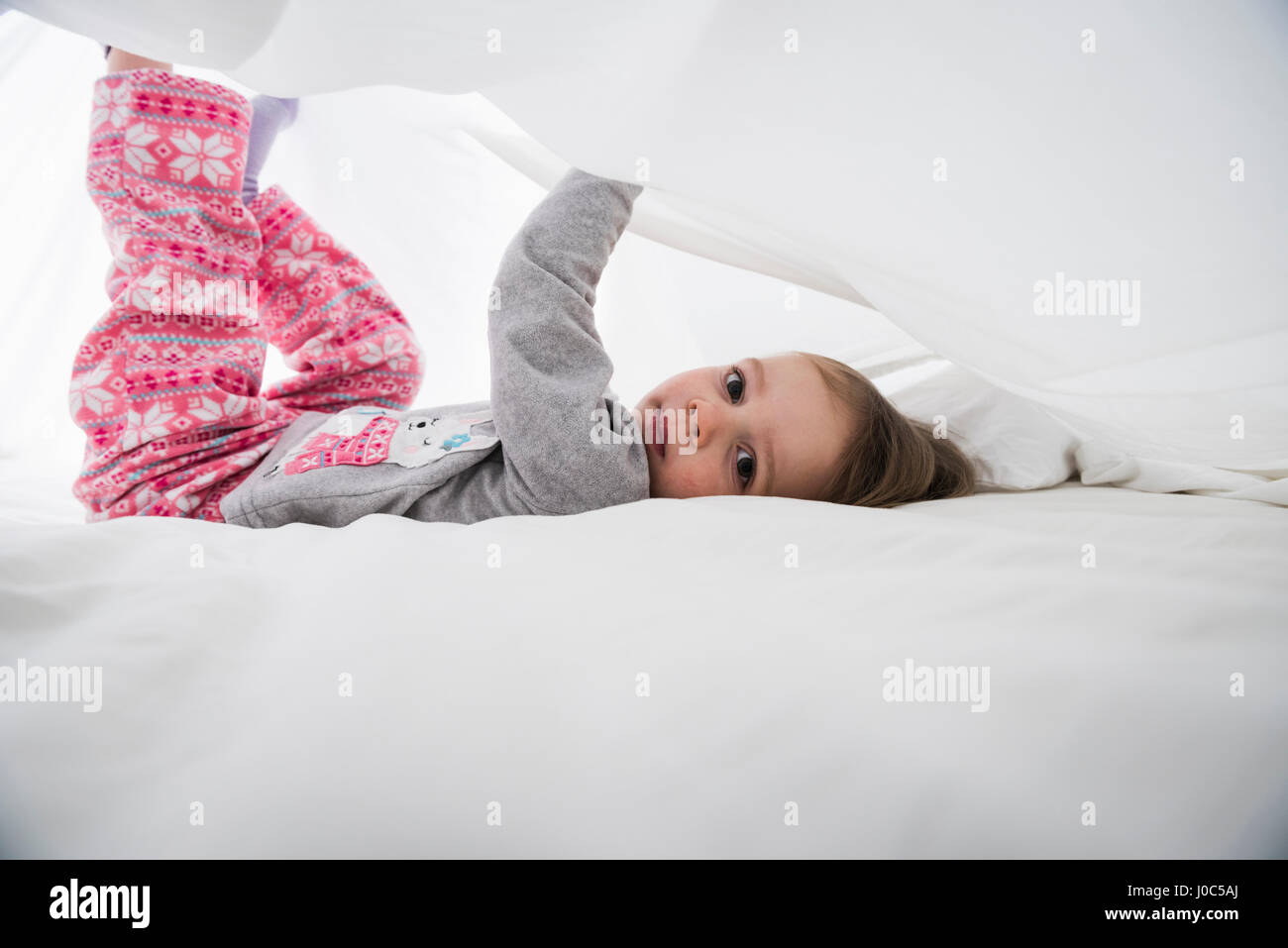 Porträt von weiblichen Kleinkind liegen zwischen weißen Bettwäsche Stockfoto