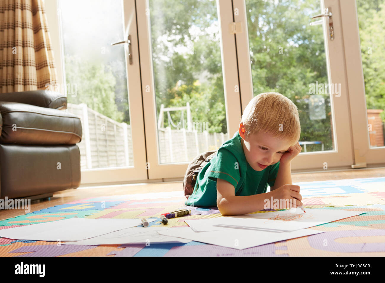 Junge auf Boden Zeichnung auf Papier Stockfoto