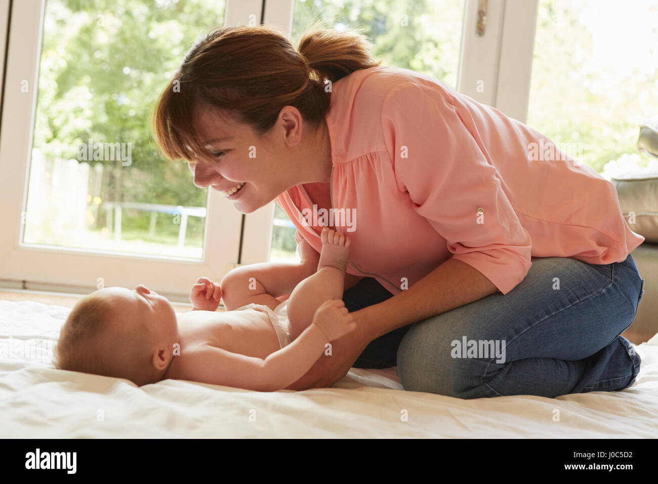 Mitte Erwachsene Frau kniet auf dem Boden spielen mit Baby Sohn Stockfoto