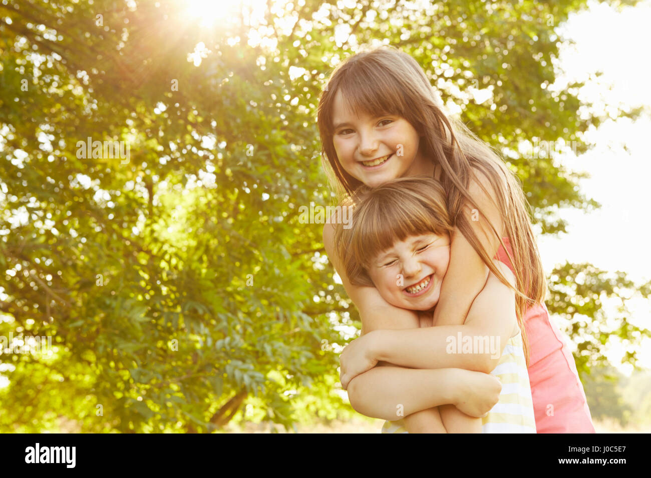 Porträt eines Mädchens wird durch große Schwester im Park umarmt Stockfoto