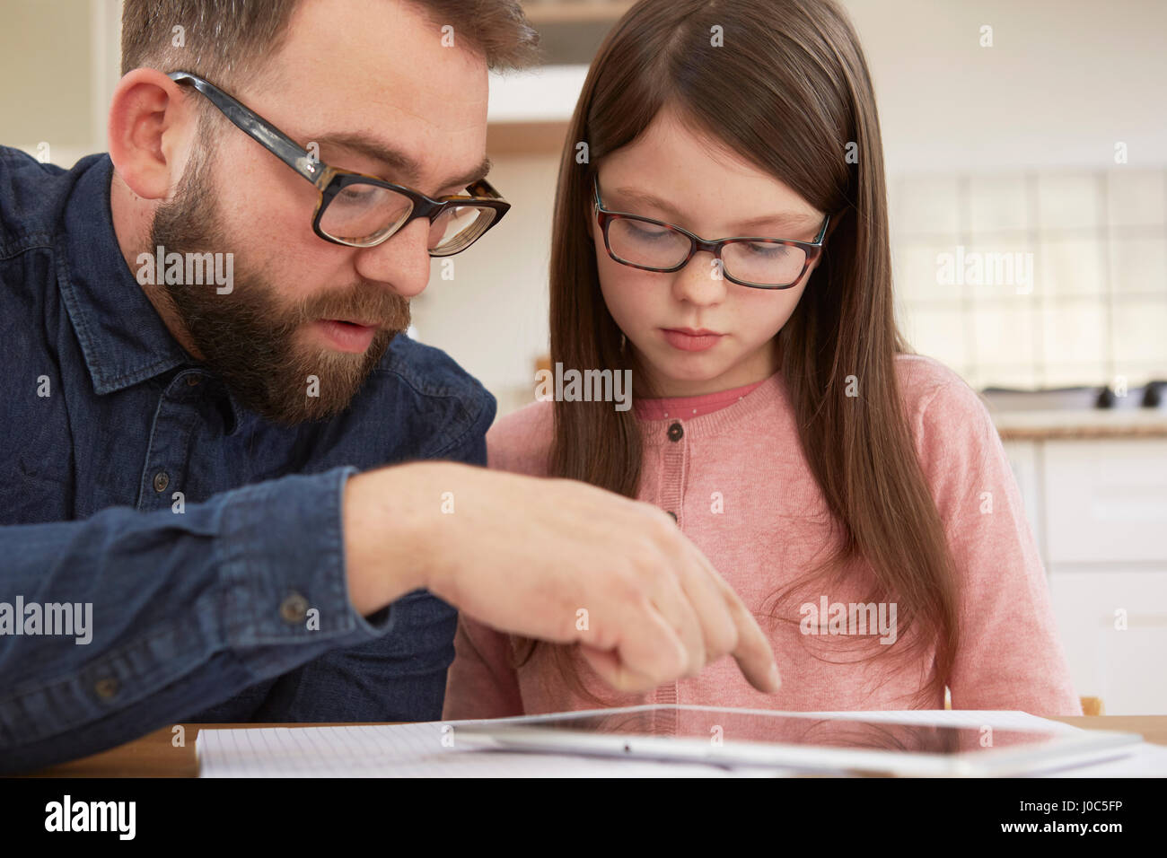 Mitte erwachsenen Mannes Hausaufgaben, Tochter am Tisch zu erklären Stockfoto