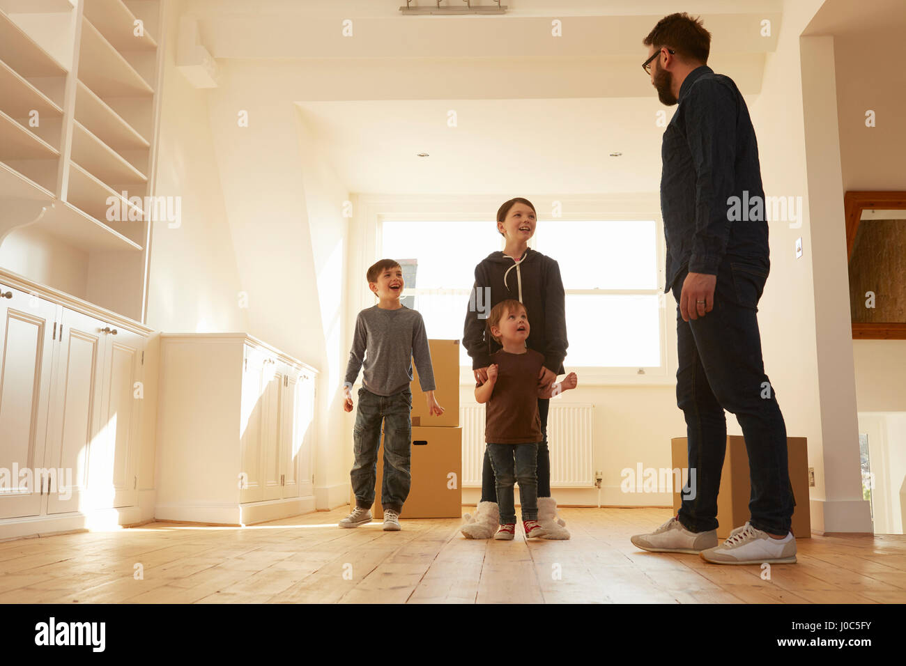 Mitte erwachsener Mann organisieren drei Kinder im neuen Zuhause Stockfoto