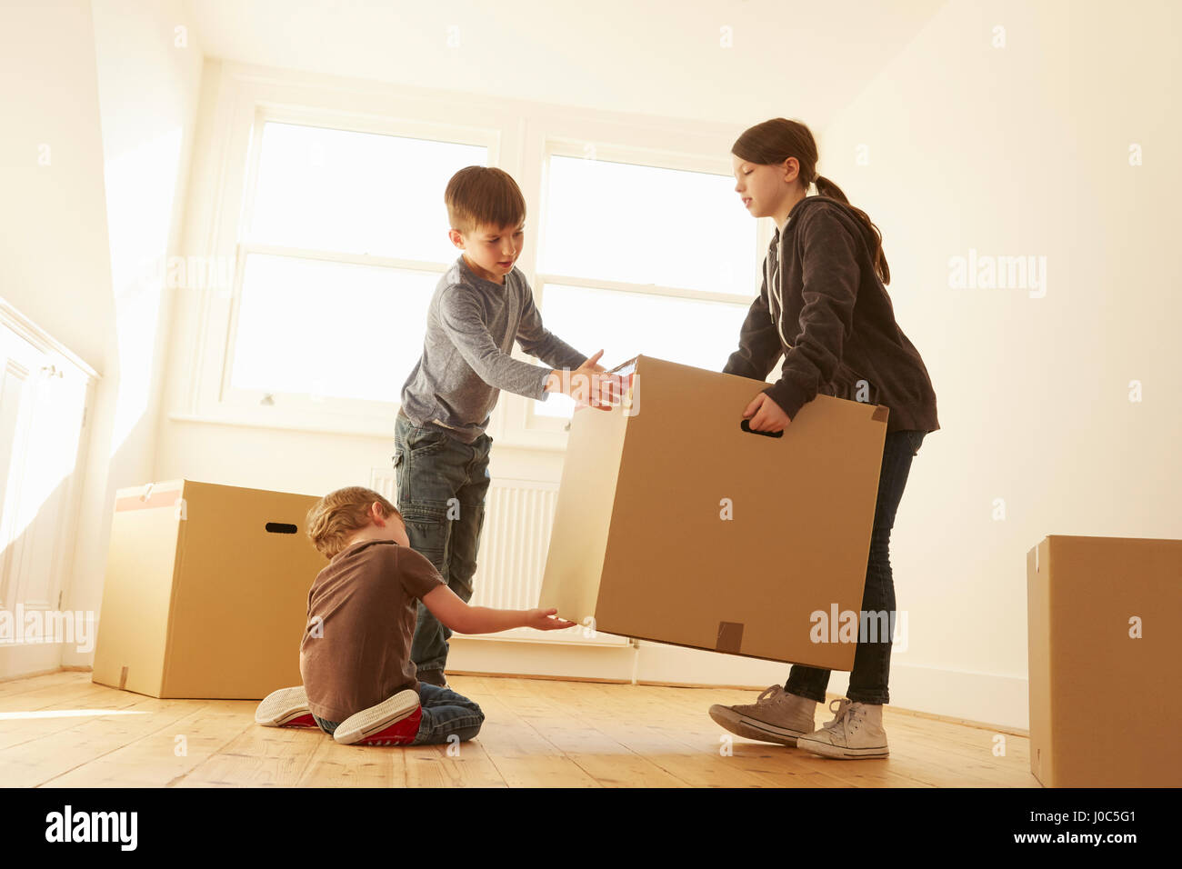 Mädchen und zwei Brüder heben Karton box im neuen Zuhause Stockfoto