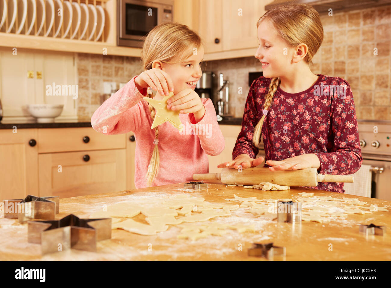 Zwei Mädchen Backen Sternform Gebäck am Küchentisch Stockfoto