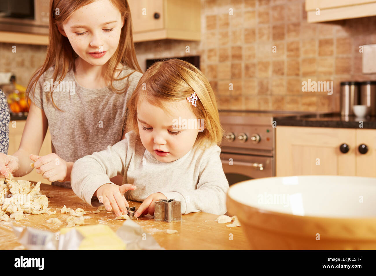 Weiblichen Kleinkind und große Schwester machen Sternform Gebäck am Küchentisch Stockfoto