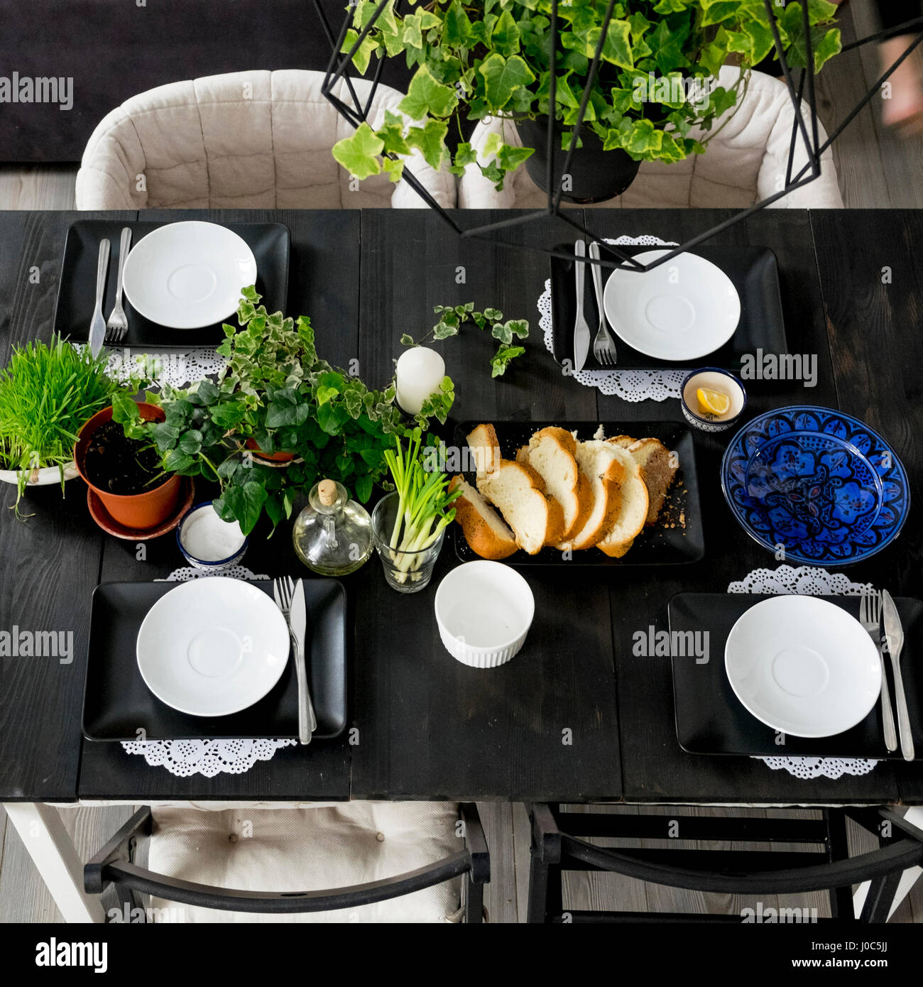 Draufsicht der gedeckten Tisch mit Brotscheiben, frischen Kräutern und Frühlingszwiebeln Stockfoto