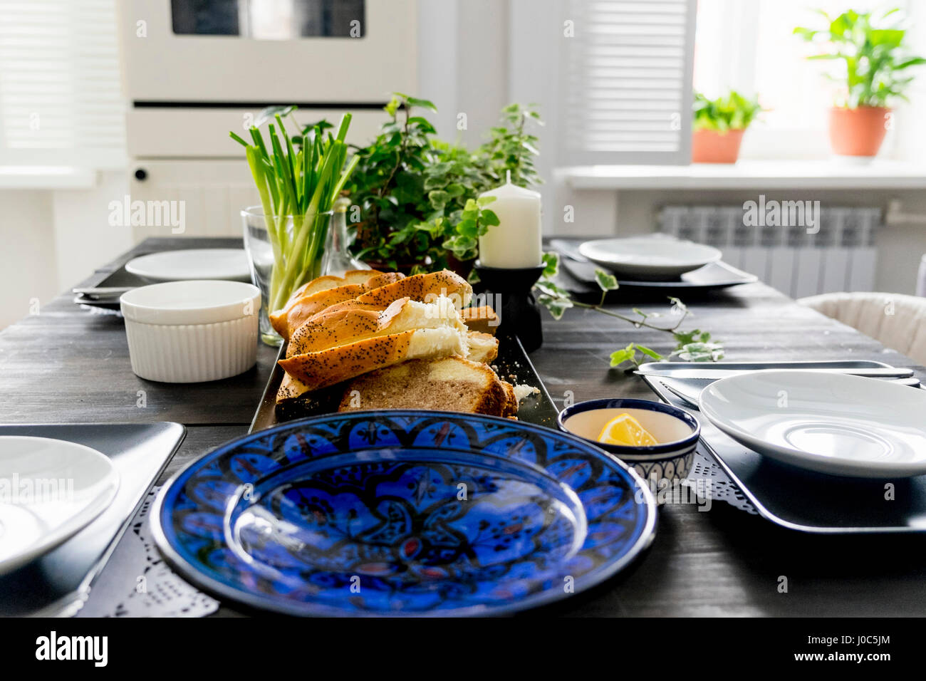 Eingestellten Küchentisch mit Brotscheiben, frischen Kräutern und Frühlingszwiebeln Stockfoto
