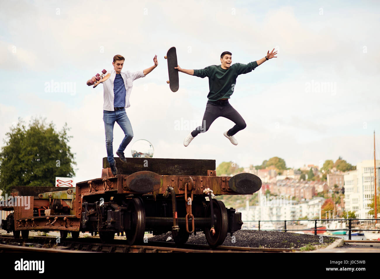 Zwei junge Männer springen aus Trailer auf Bahnstrecke, Bristol, UK Stockfoto