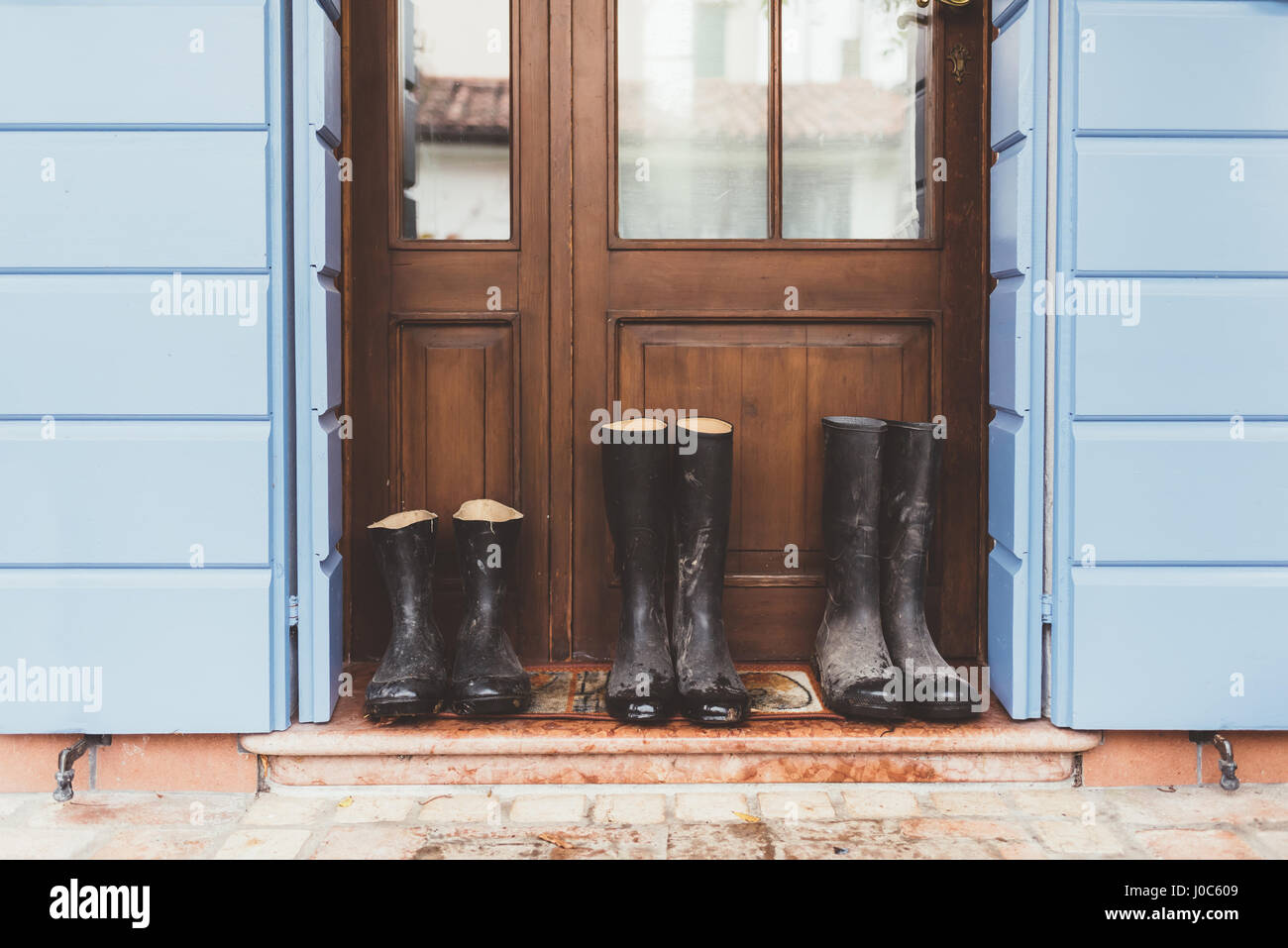 Drei Paare von Gummistiefeln vor Haustür Stockfoto