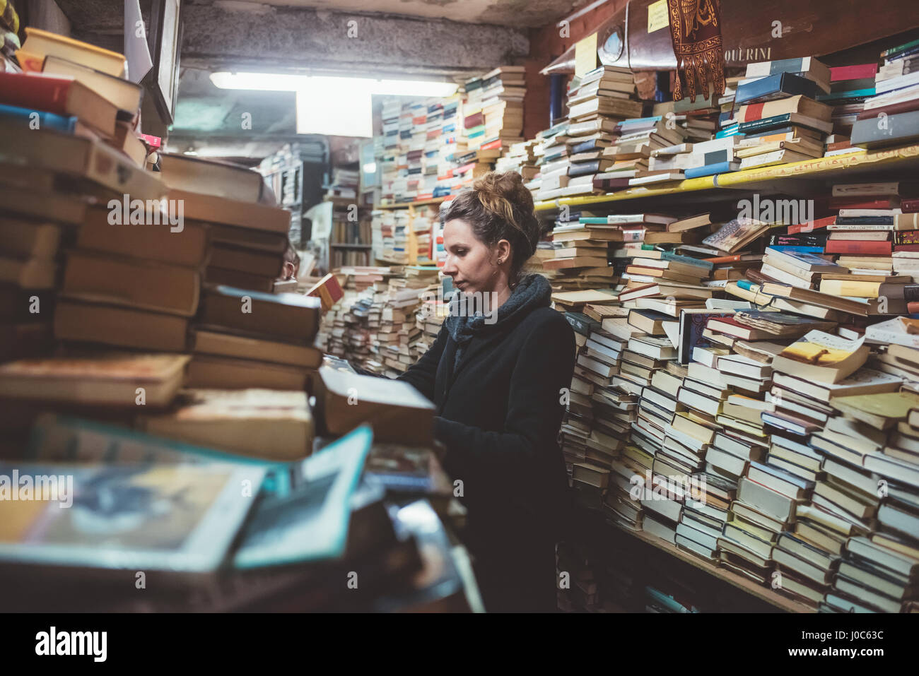 Junge Frau Surfen in gestapelten Buchladen, Venedig, Italien Stockfoto