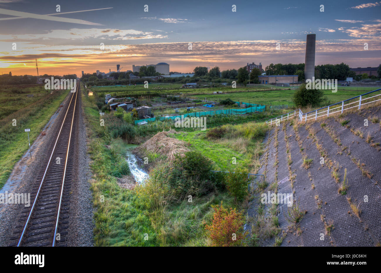 Eine Bahnstrecke, die gehen in die Industriegebäude der Stadt bei Sonnenuntergang in Groningen, The Netherlands. Stockfoto