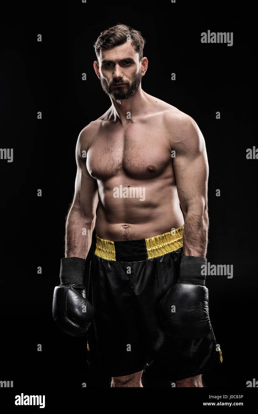 Junge muskulöse Sportler in Boxhandschuhen und Blick in die Kamera am schwarzen shorts Stockfoto