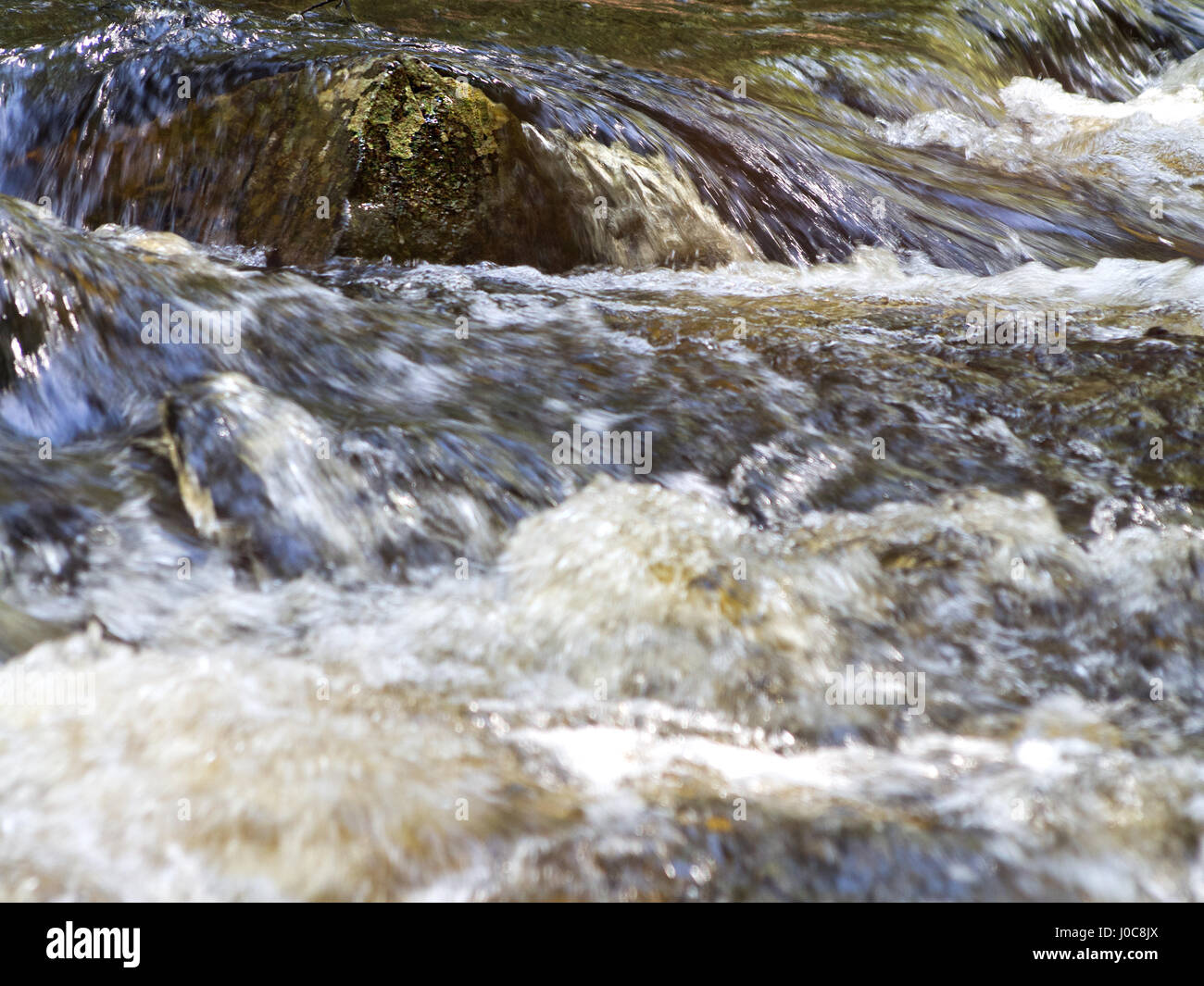 Ein Felsen mit Wasser fließt es in einen reißenden Fluss in Bear Brook State Park in der Nähe von Allentown, New Hampshire. Stockfoto