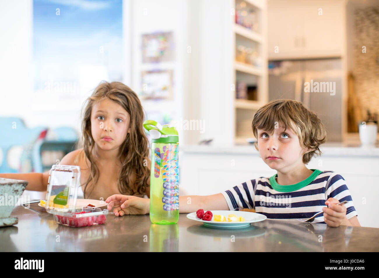 Jungen und Mädchen am Küchentisch Grimassen Stockfoto