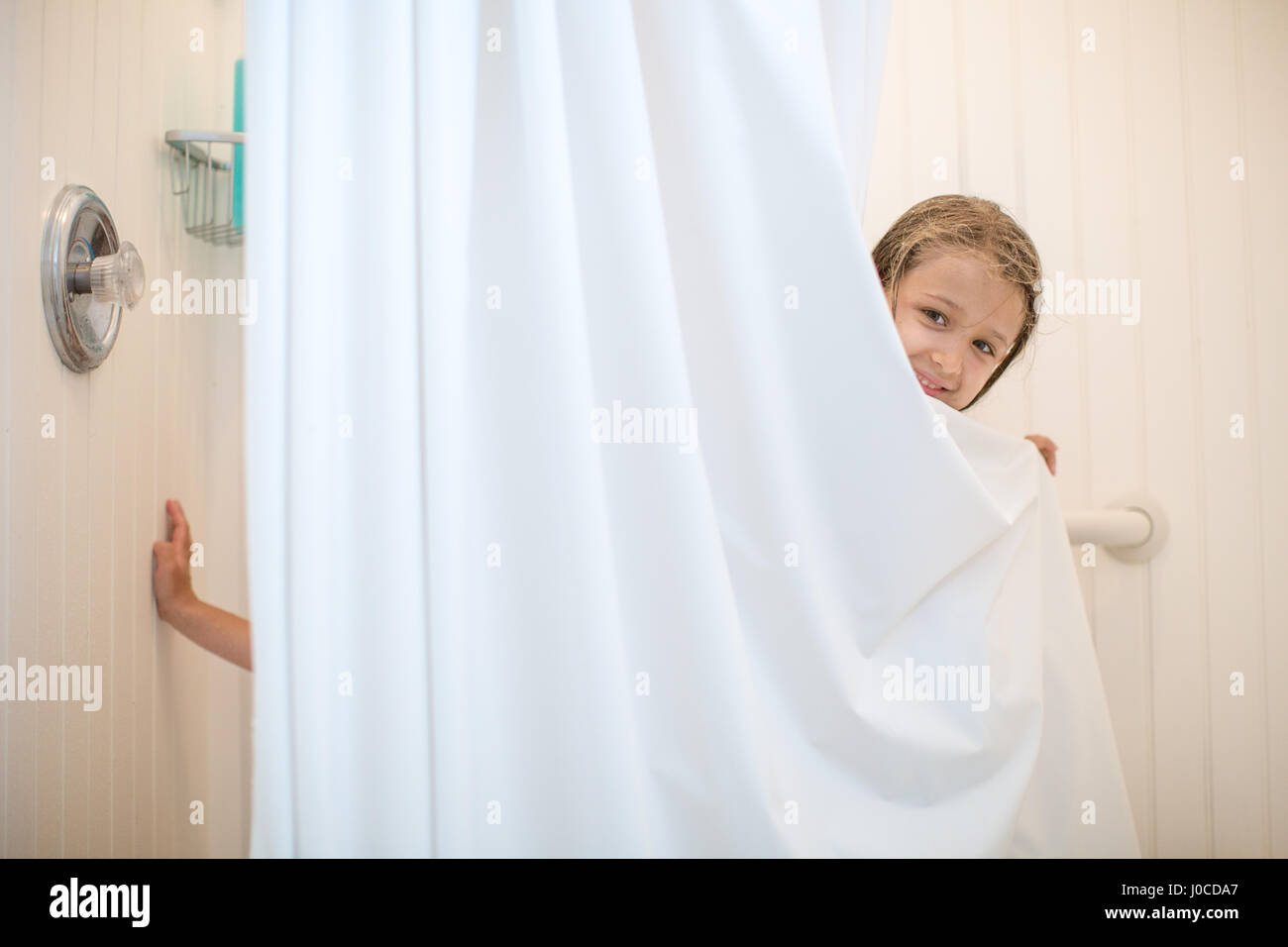 Porträt eines Mädchens peering von Duschvorhang Stockfoto