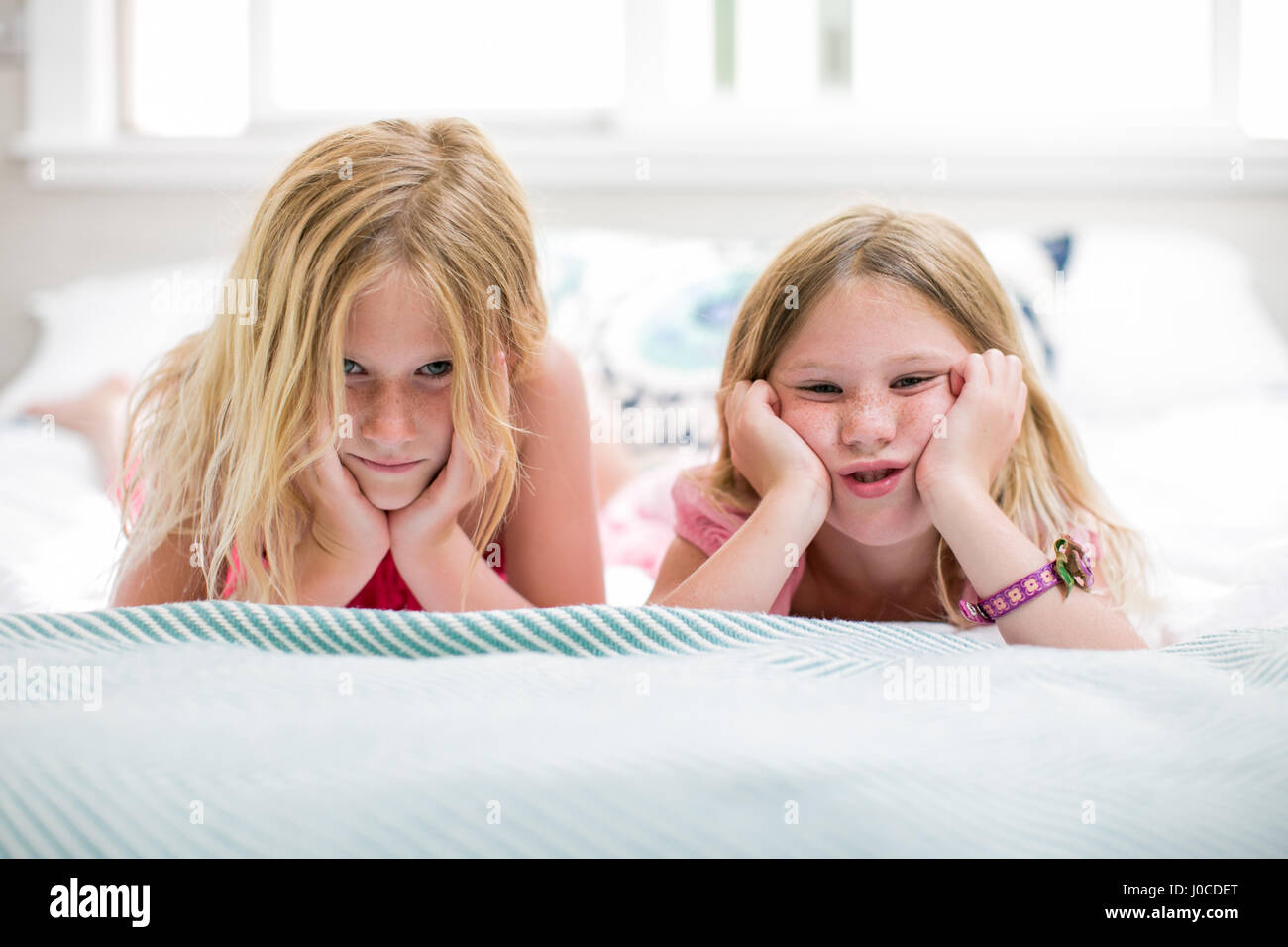 Porträt von Mädchen und Schwester Grimassen auf Bett Stockfoto