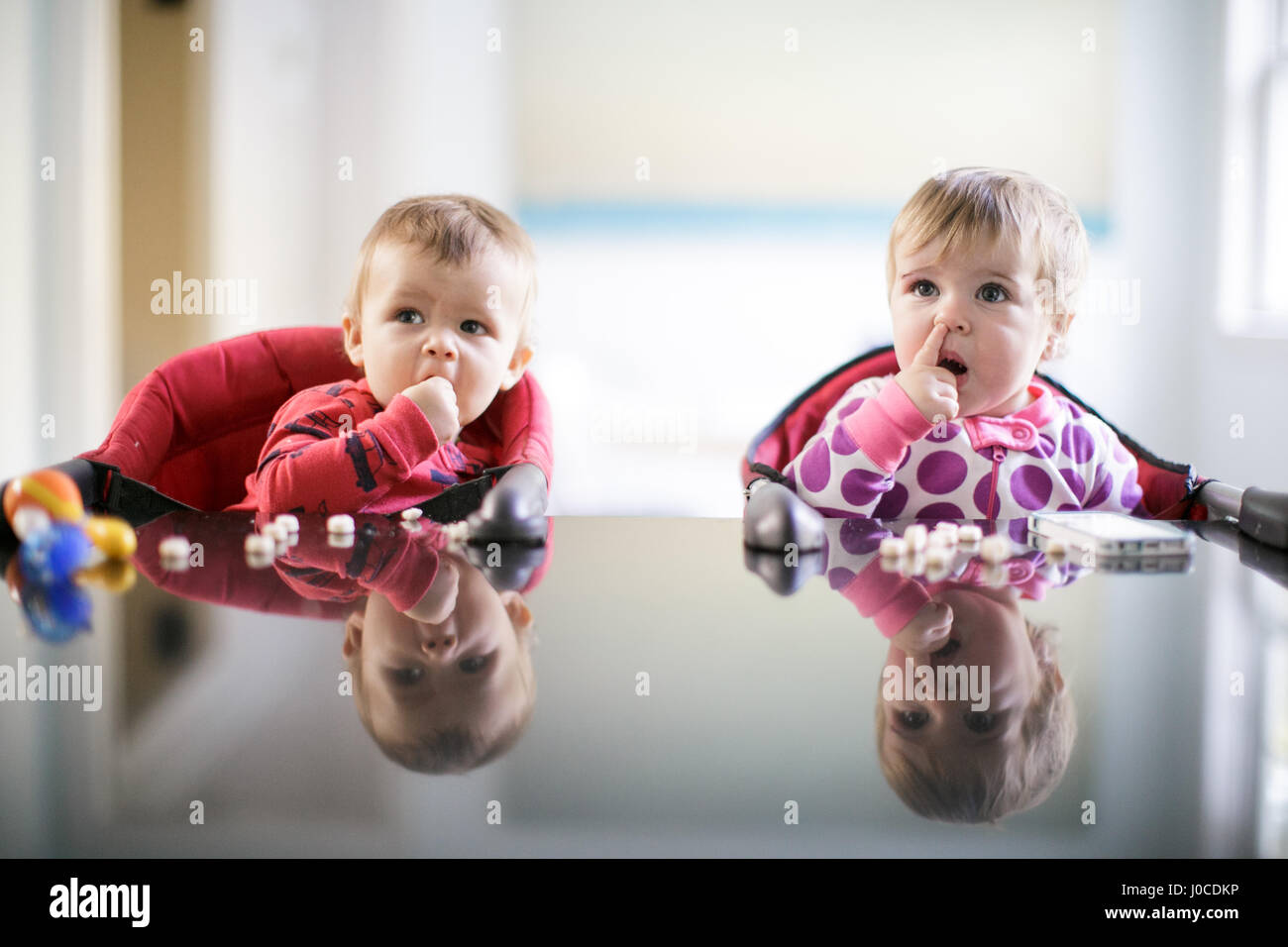 Männliche und weibliche Kleinkinder am Küchentisch Kommissionierung Nase und Süßigkeiten essen Stockfoto