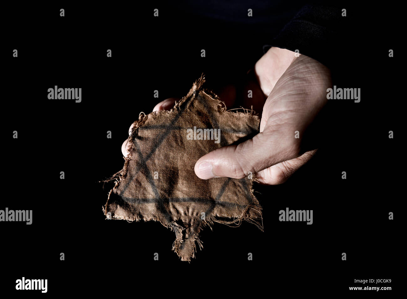 Nahaufnahme eines zerlumpten jüdisches Abzeichen in der Hand eines Mannes Stockfoto