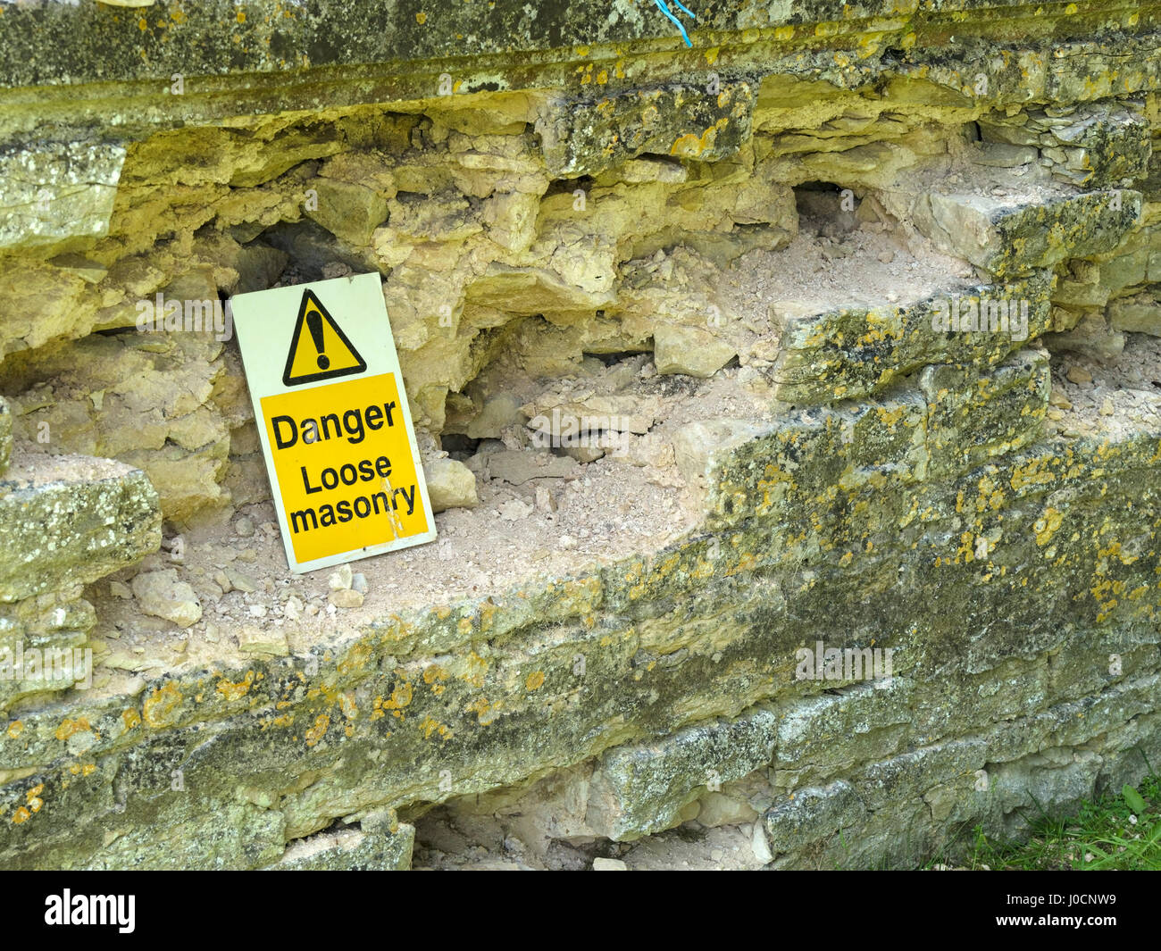 "Gefahr lose Mauerwerk" Warnschild am Zerbröckeln Steinmauer, UK Stockfoto