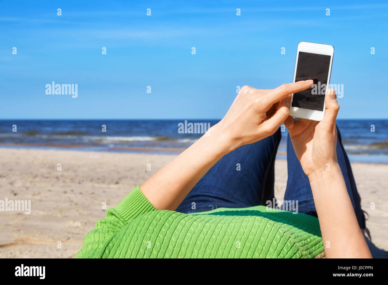 Nahaufnahme einer Frau, die mit modernen Smartphone an einem Strand, leeren Bildschirm für Textfreiraum. Stockfoto