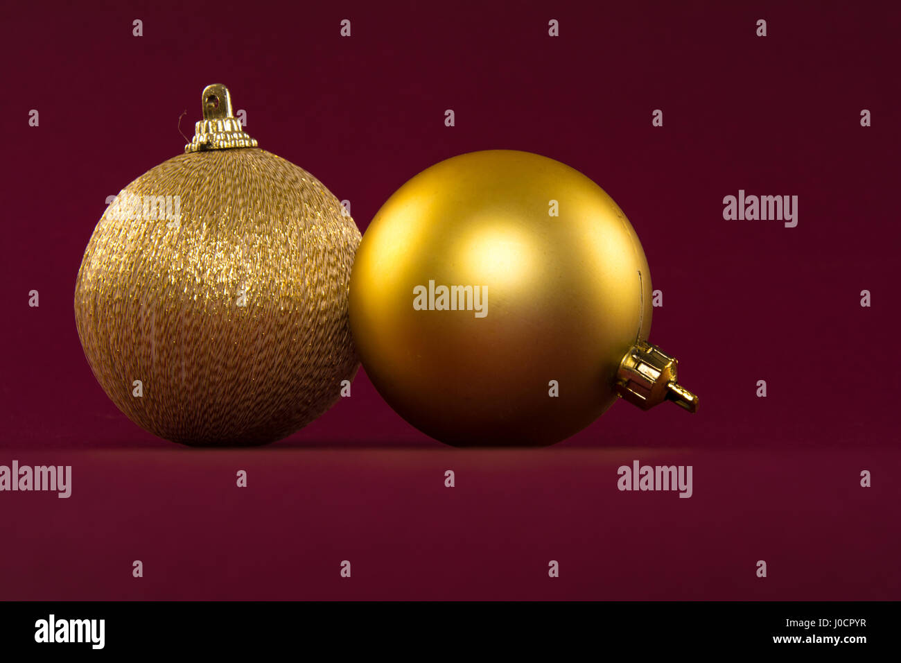 Nahaufnahme von goldenen Weihnachtskugeln auf rotem Grund Stockfoto