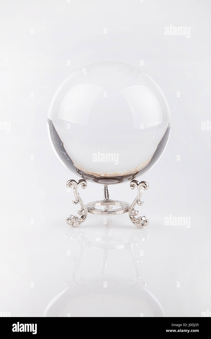 Klare Glaskugel auf einem silbernen Ständer auf einer weißen Fläche. Kristallkugel isoliert auf weißem Hintergrund. Stockfoto