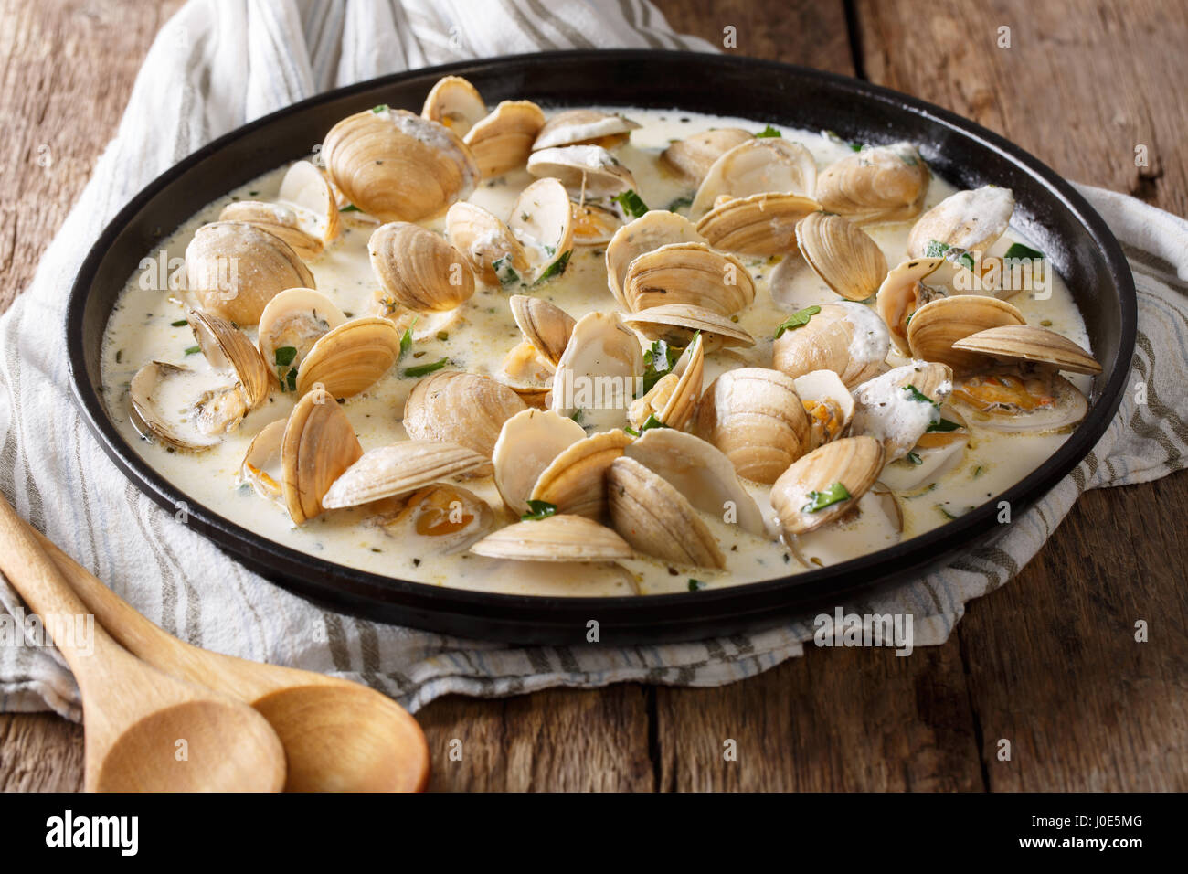 Leckere Muscheln in einer cremigen Sauce mit Knoblauch und grünen Nahaufnahme auf einem Teller auf den Tisch. horizontale Stockfoto