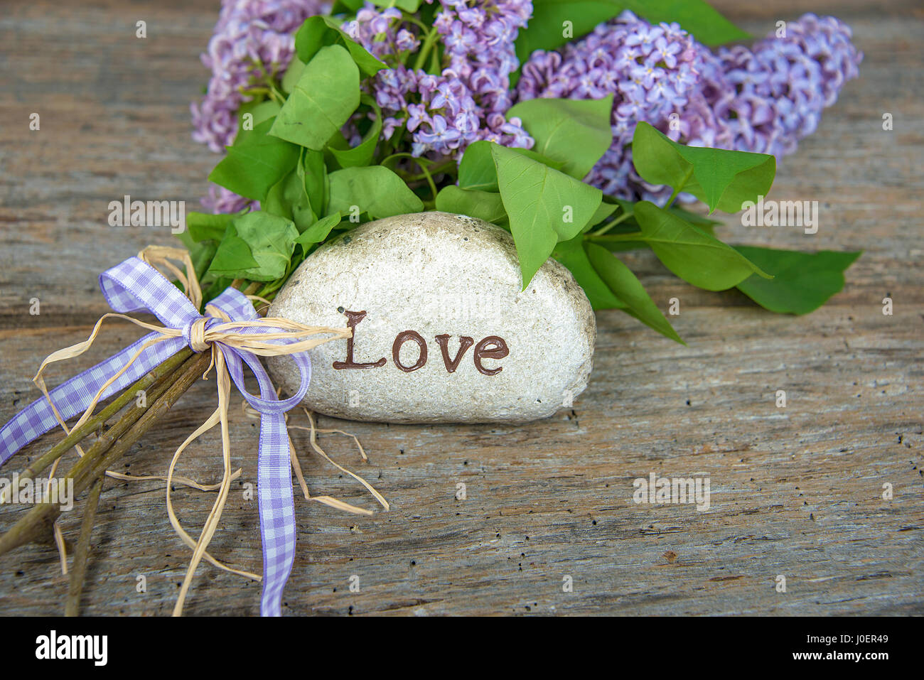 Wort-Liebe auf Stein mit lila bouquet Stockfoto