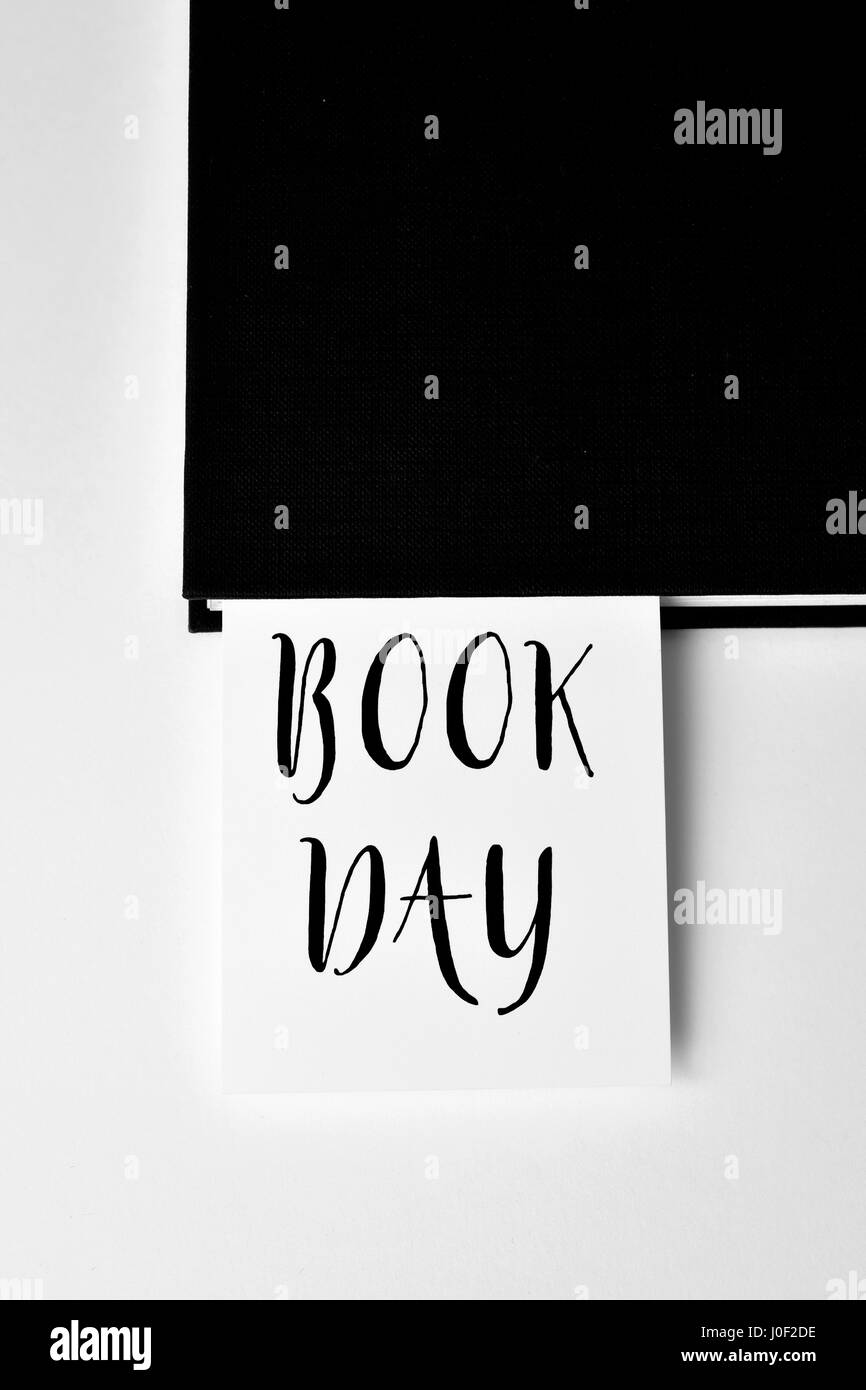 Nahaufnahme von einem Stück Papier mit dem Text-Buch-Tag auftauchen aus einem Buch, platziert auf einer weißen Fläche Stockfoto