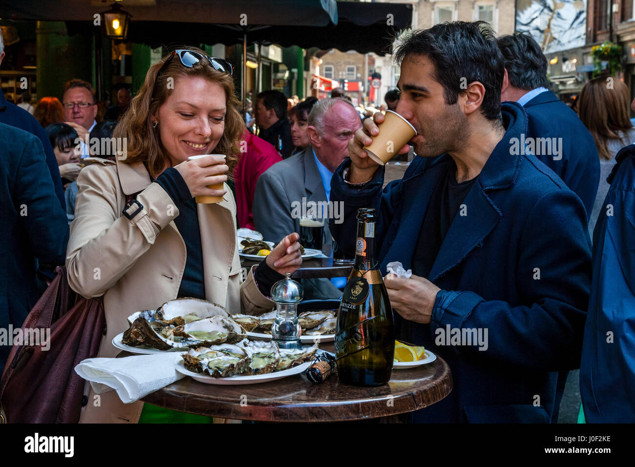 Zwei Personen genießen, Prosecco und Austern, die außerhalb einer Gaststätte in Borough Market, London, England Stockfoto