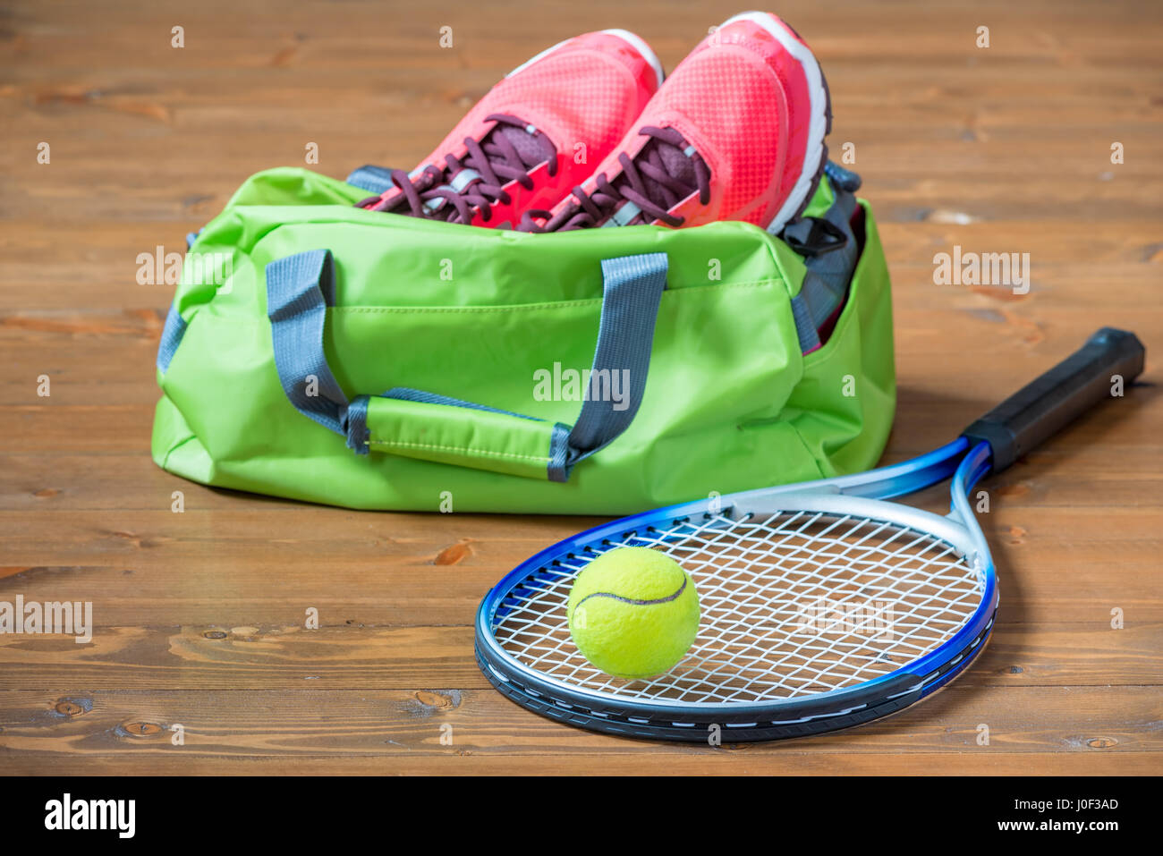 Schläger und Ball für Tennis im Fokus auf dem Hintergrund der Tasche mit Turnschuhen auf dem Boden Stockfoto