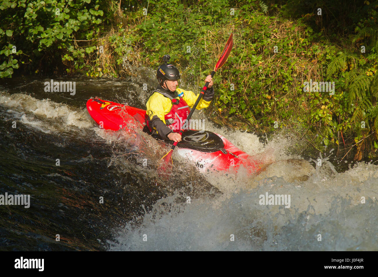 Männliche kayaker Paddeln durch die Stromschnellen des Flusses Tryweryn auf nationaler White Water Centre in der Nähe von Bala in Nord Wales Stockfoto