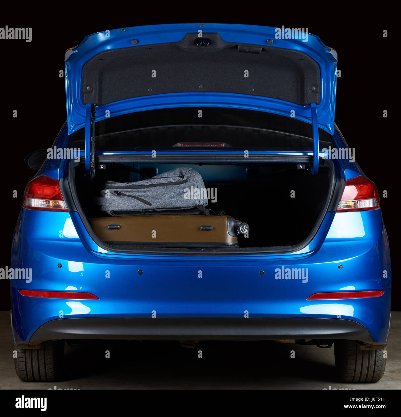 Moderne blaue Limousine Kofferraum voll mit Gepäcktaschen auf schwarzem Hintergrund isoliert Stockfoto