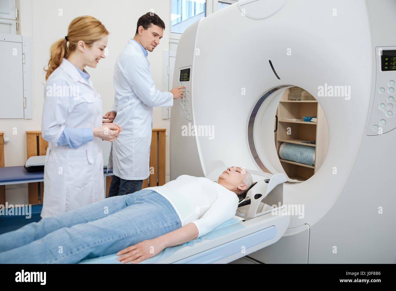 Macht nichts. Gut aussehend erfahrenen männlichen Arzt seine Patienten zu betrachten und durch Drücken der Taste während der Verwendung von CT-scanner Stockfoto