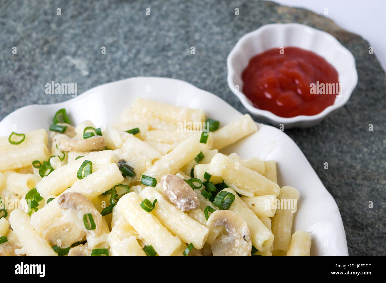 Makkaroni-Nudeln mit Zwiebel in Scheiben geschnitten Rollen und Tomatensauce Stockfoto