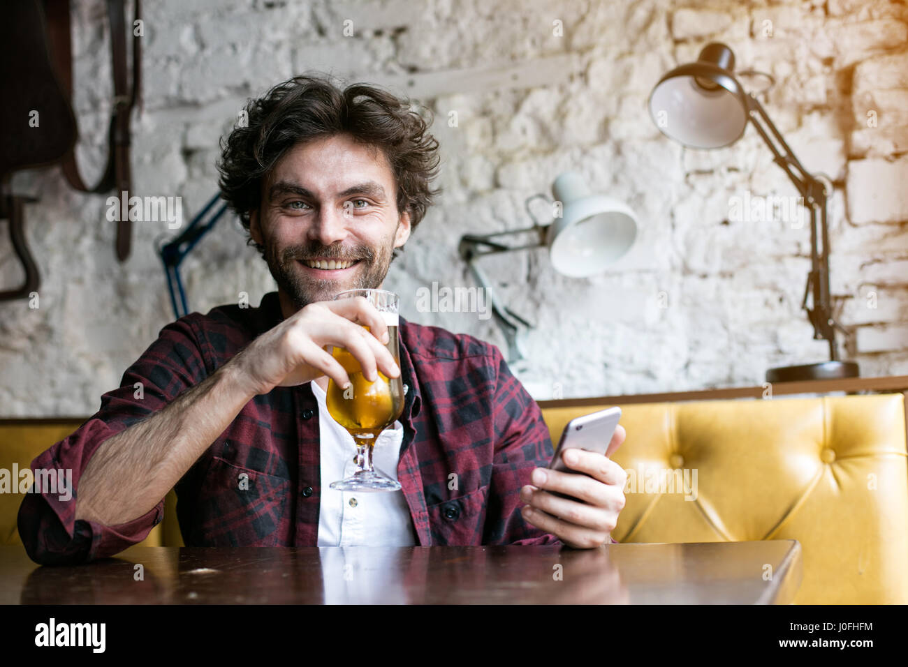 attraktiver Mann entspannen und haben ein Bier in einem Pub und mit seinem Handy Stockfoto