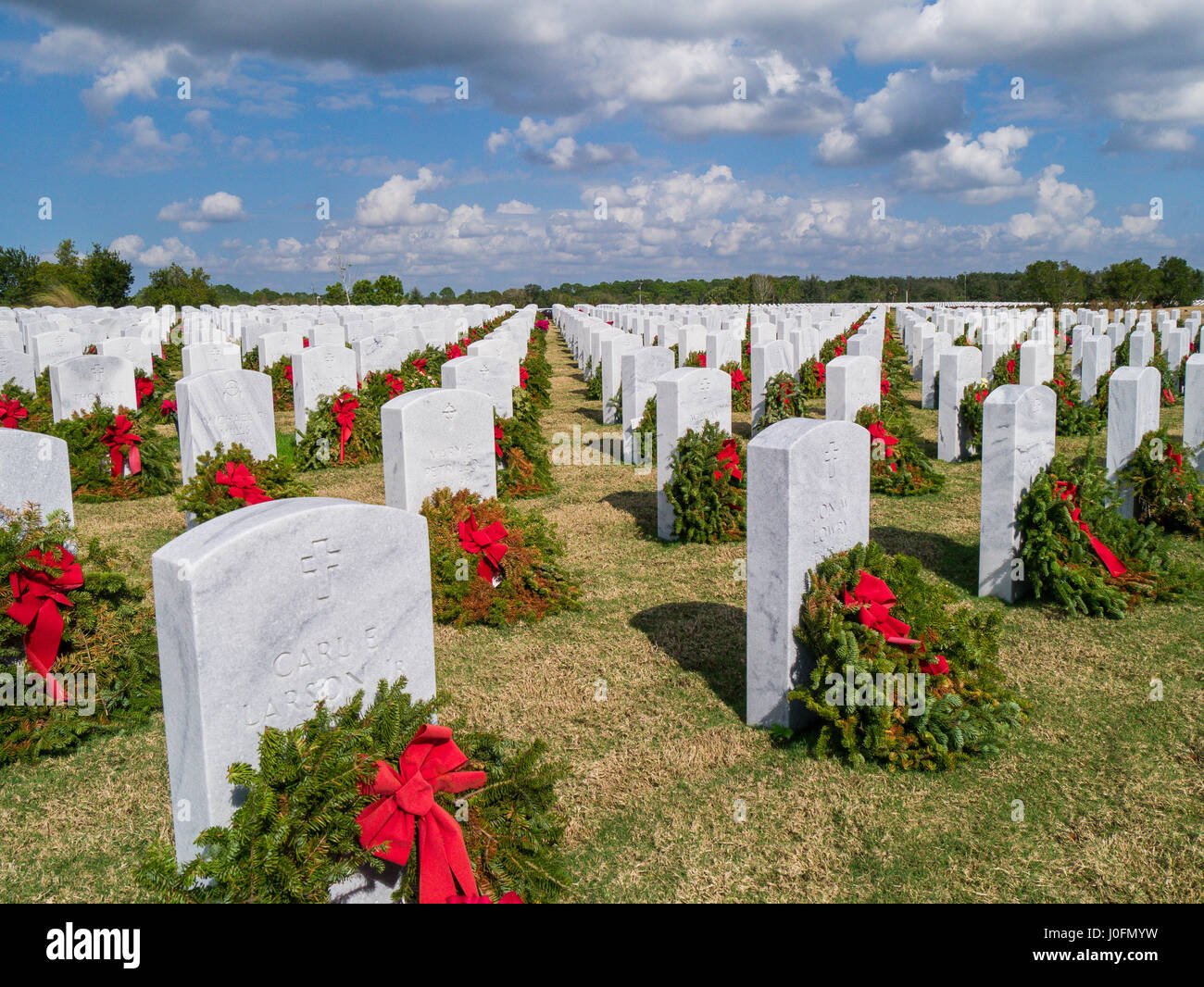 Reihen von Grabsteinen mit Kränzen & roten Bögen in Sarasota National Cemetery in Sarasota Florida Stockfoto