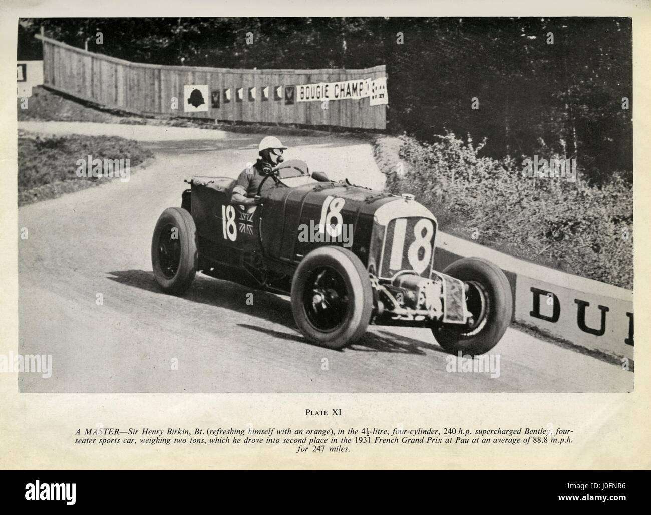 Sir Henry Birkin, konkurrieren in 1931 Grand Prix von Frankreich, saugt an einer Orange, während er einen aufgeladenen Bentley fährt Stockfoto