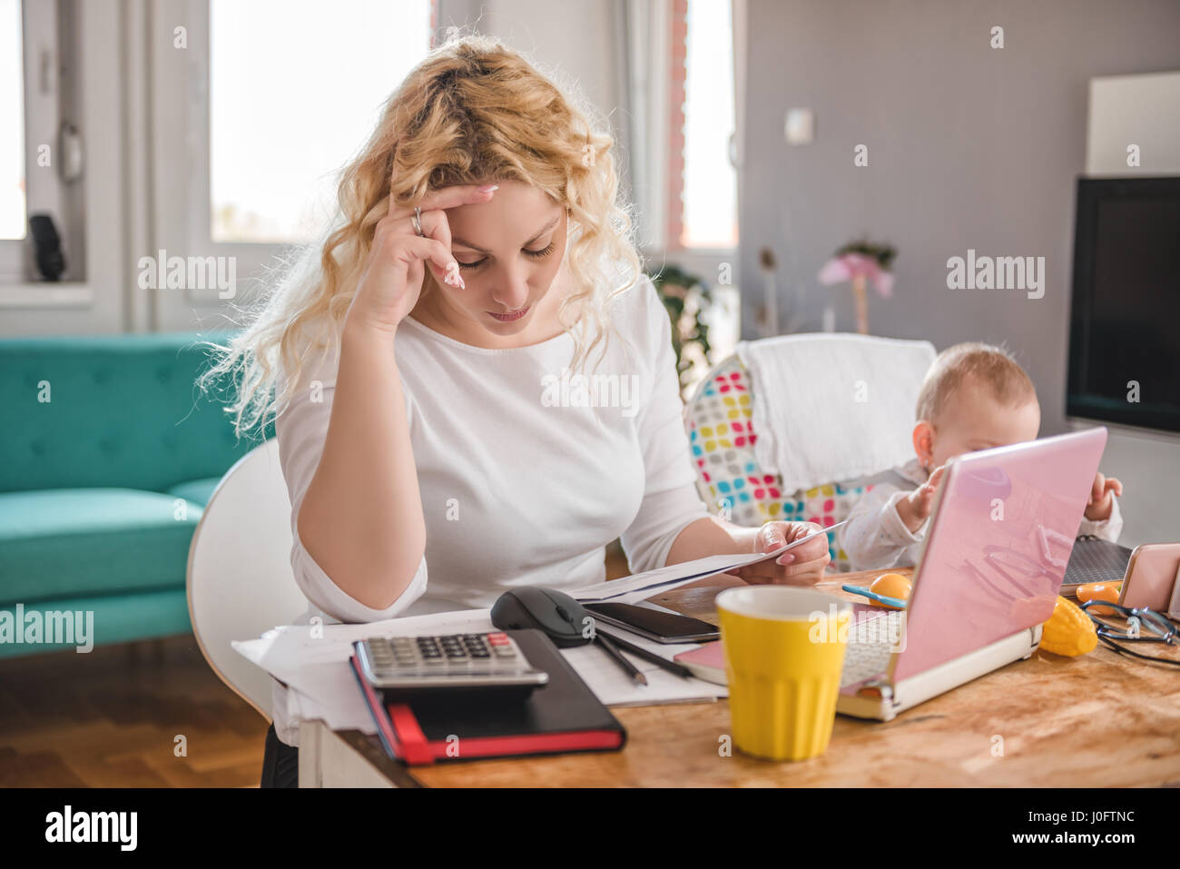 Besorgte Mutter betrachten Umschlag zu Hause, Büro und kümmert sich um ihr baby Stockfoto