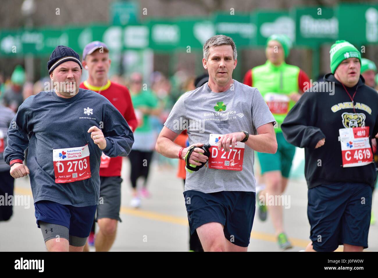 Männer, die unter einem Meer von Läufern, wie sie Ansatz, der die Ziellinie am Shamrock Shuffle Rennen in Chicago, Illinois, USA 2017. Stockfoto