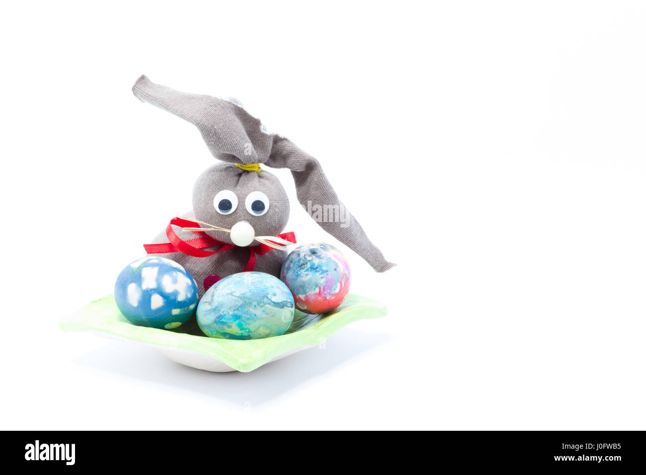 Osterhase braun Tuch und drei hand farbige Ostereier - abstrakte Farben gelb, blau, grün, rot, rosa, lila, Orange mit Streifen in isoliert Stockfoto