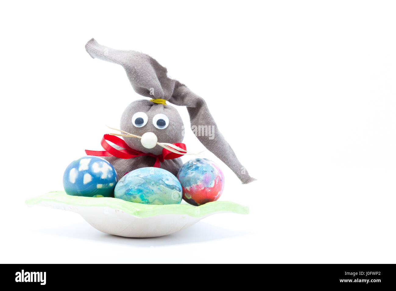 Braunem Tuch mit roten Band Osterhasen und drei hand farbige Ostereier - abstrakte Farben gelb, blau, grün, rot, rosa, lila, Orange mit stri Stockfoto