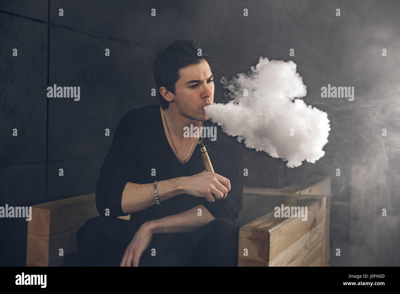 Dampfen Mann hält eine mod. Eine Wolke aus Dampf. Schwarzer Hintergrund. Stockfoto