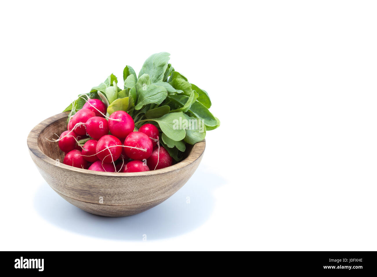 Frische Radieschen mit grünen Blättern in einer natürlichen Holz Schüssel in weißen Hintergrund isoliert Stockfoto