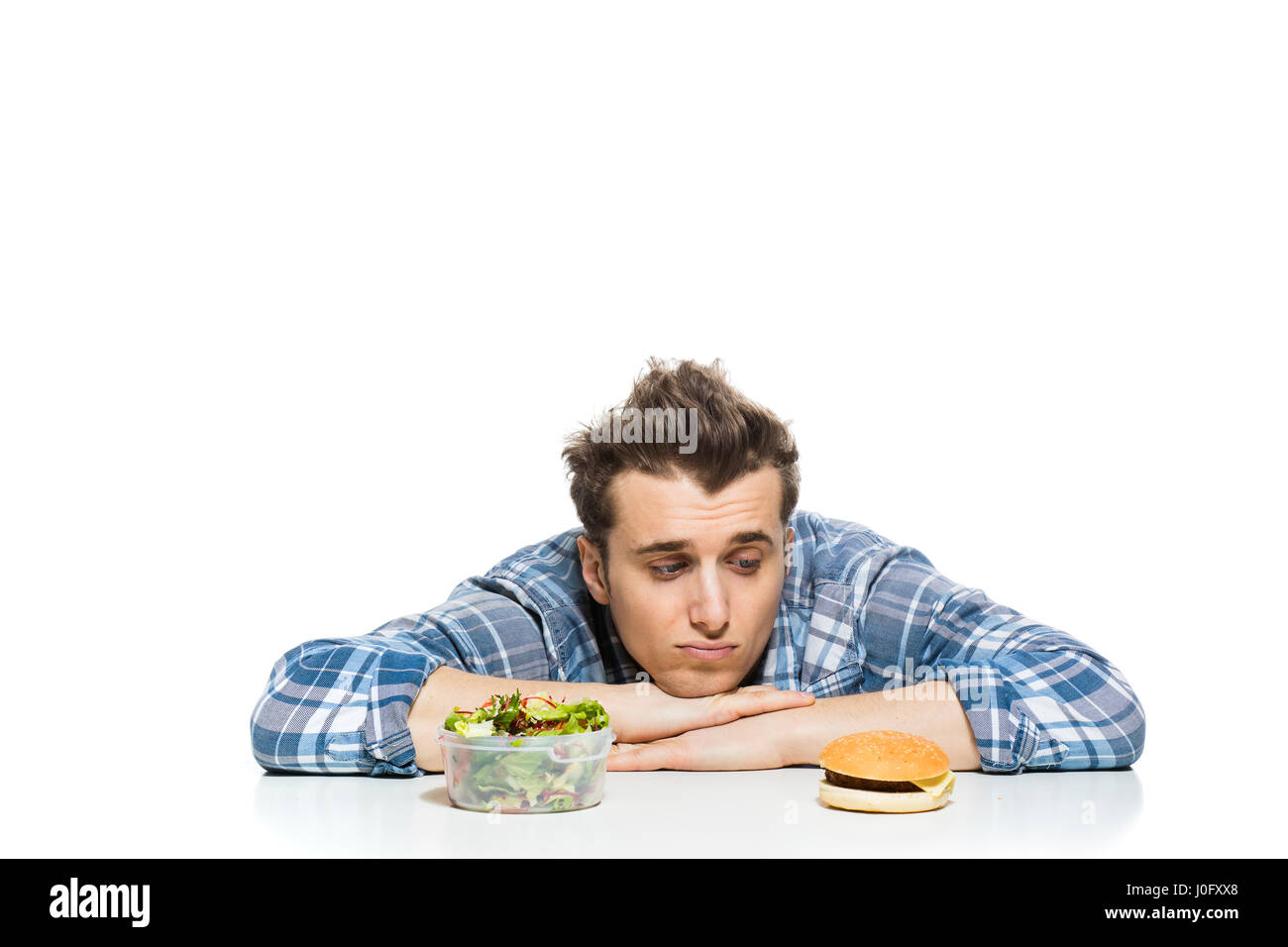 Fastfood im Vergleich zu gesunden Lebensmitteln Konzept mit jungen Mann mit vorne zwei Entscheidungen, Salat und Fast-Food, isoliert auf weiss Stockfoto