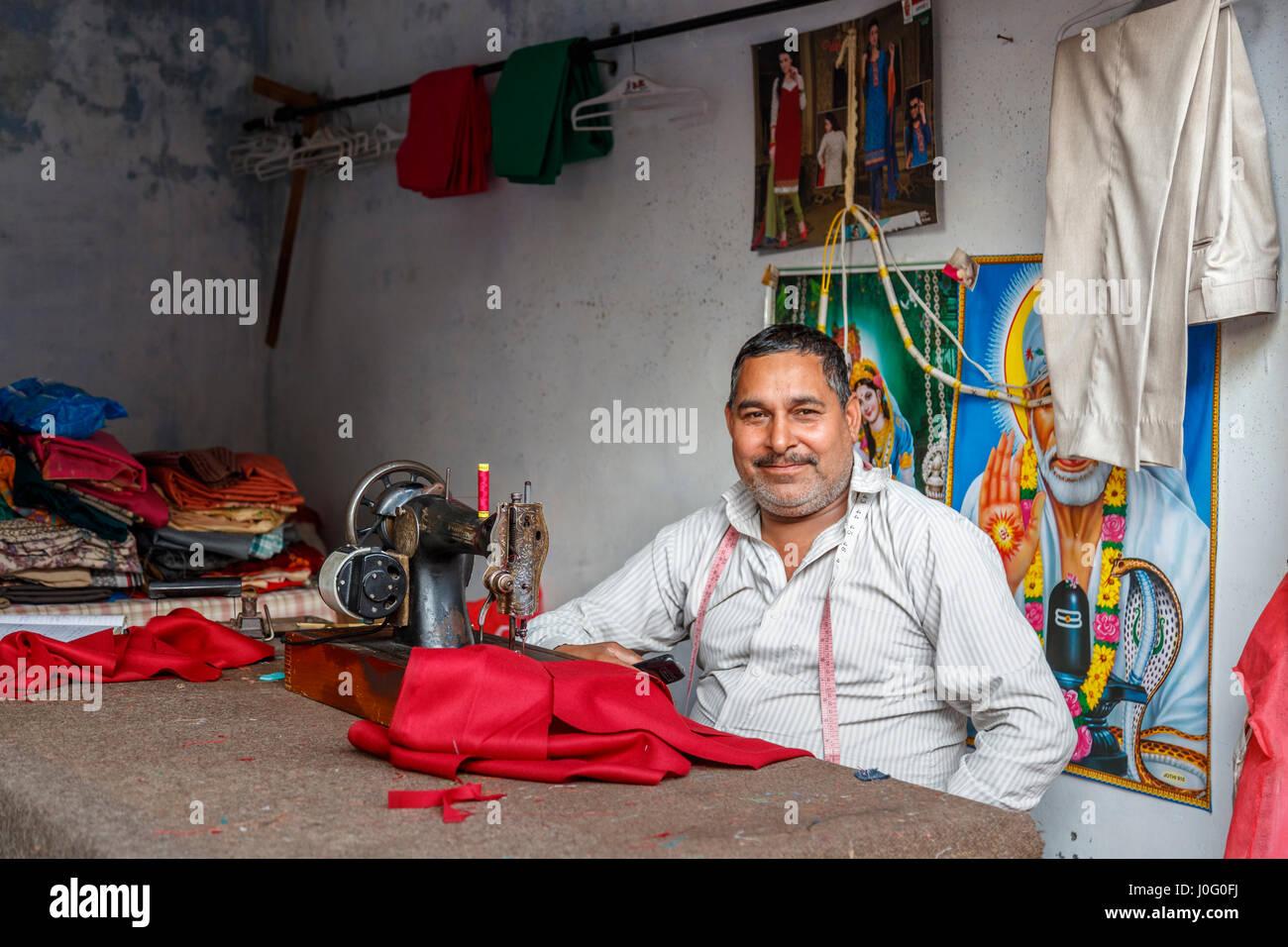 Freundlichen lokalen indischen Schneider arbeiten bei einer traditionellen Nähmaschine, Pragpur, ein Kulturerbedorf im Kagra Bezirk, Himachal Pradesh, Indien Stockfoto
