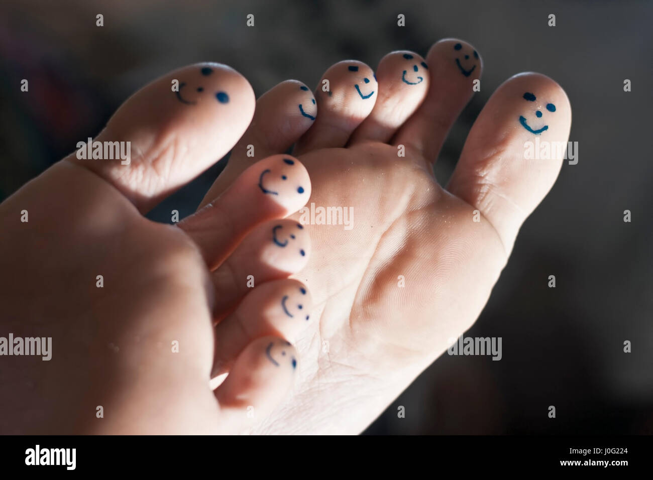 Smiley-Gesichter auf menschlicher Fuß mit schwarzem Stift gezeichnet ...